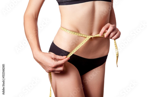 Slim fit happy young woman with measure tape measuring her waist with black underwear  isolated on white background. studio shot.  