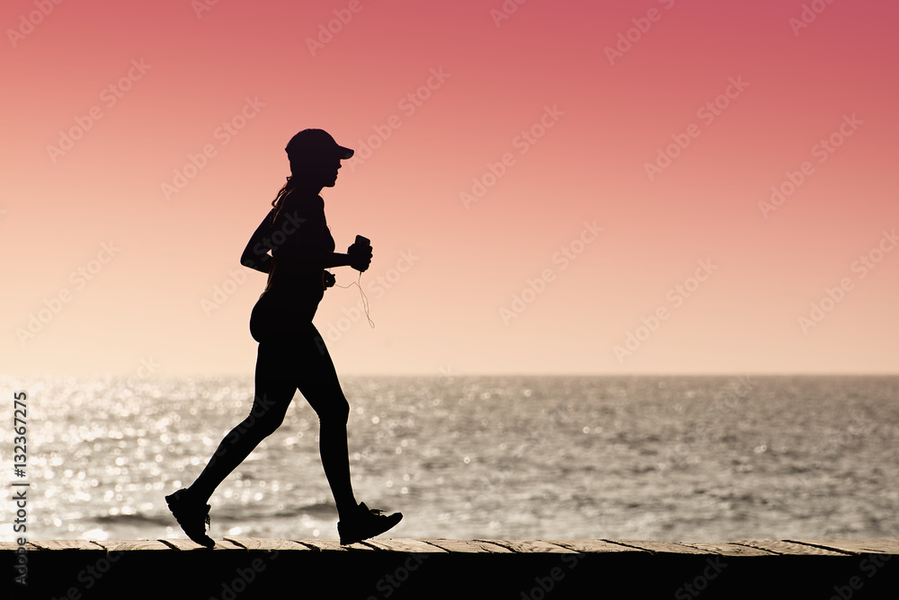 Silhouette young female runner,running at sunset on the sea