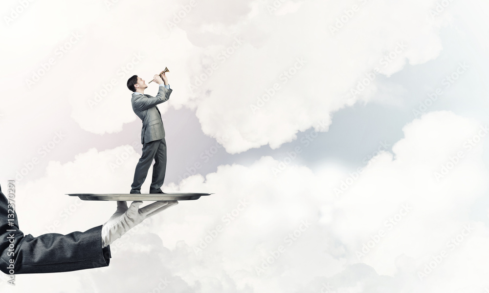 Businessman on metal tray playing fife against blue sky background Businessman on metal tray playing fife against blue sky background
