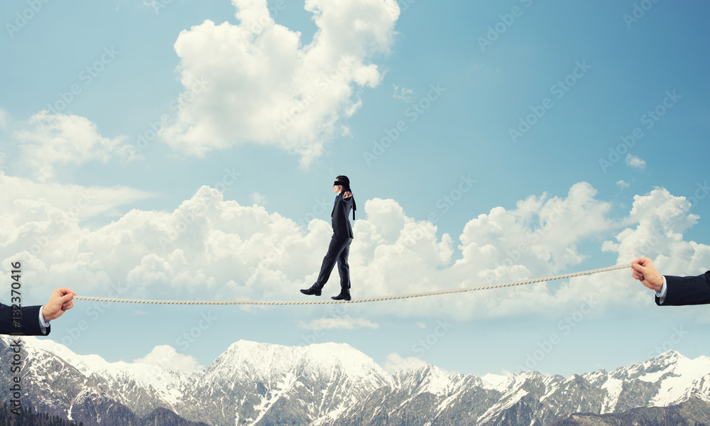 Business concept of risk support and assistance with man balancing on rope Business concept of risk support and assistance with man balancing on rope