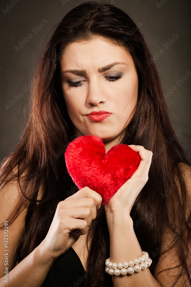 Sad lovely woman holds red heart on black Sad lovely woman holds red heart on black