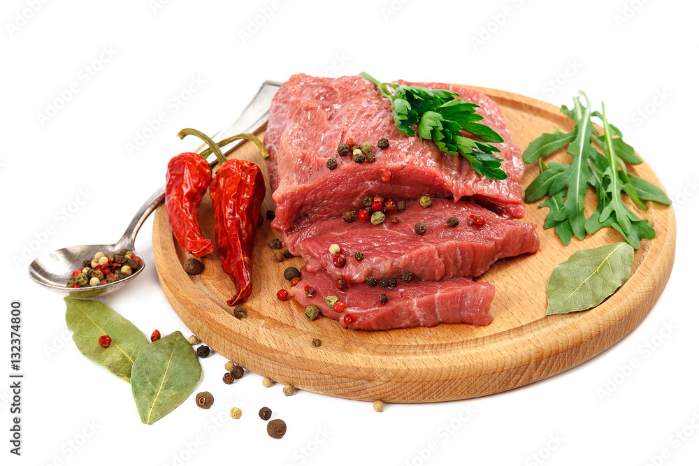 Meat on a cutting board and spices on white background.