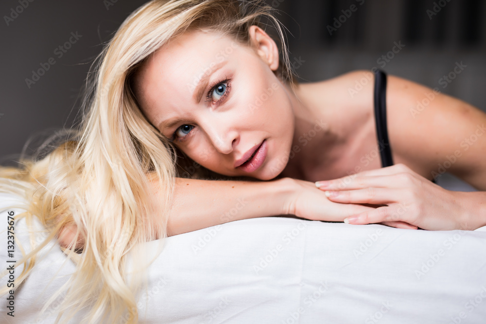 Portrait of young woman in lingerie lying in bed and looking at camera Portrait of young woman in lingerie lying in bed and looking at camera