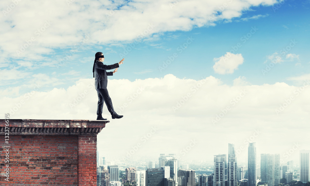 Danger and risk concept with businessman making step from edge