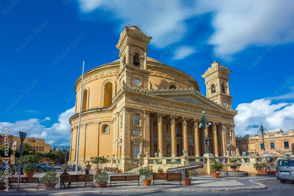 Mosta, Malta - The Church of the Assumption of Our Lady, commonly known as the Rotunda of Mosta or Mosta Dome at daylight with moving clouds and blue sky