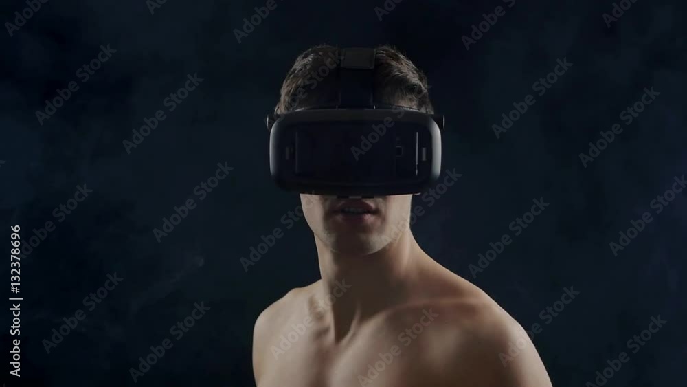 man getting experience using VR-headset, standing in dark, with smoke around him.