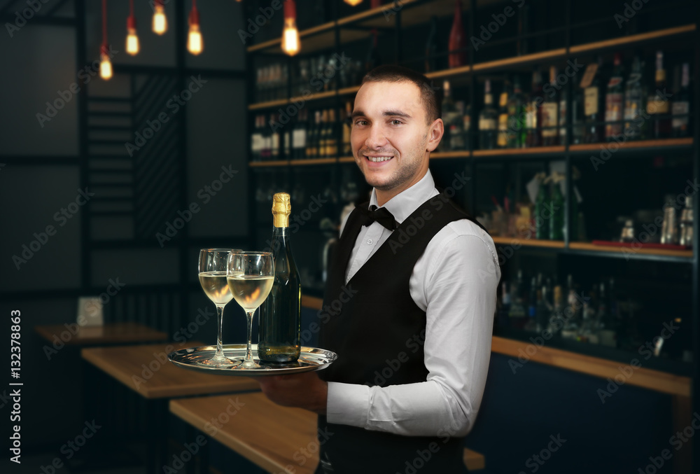 Young handsome waiter holding tray with wine glasses in the restaurant Young handsome waiter holding tray with wine glasses in the restaurant