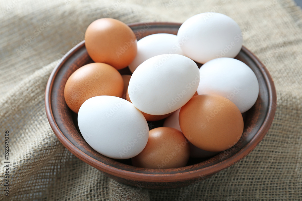 Bowl with raw eggs on fabric background Bowl with raw eggs on fabric background