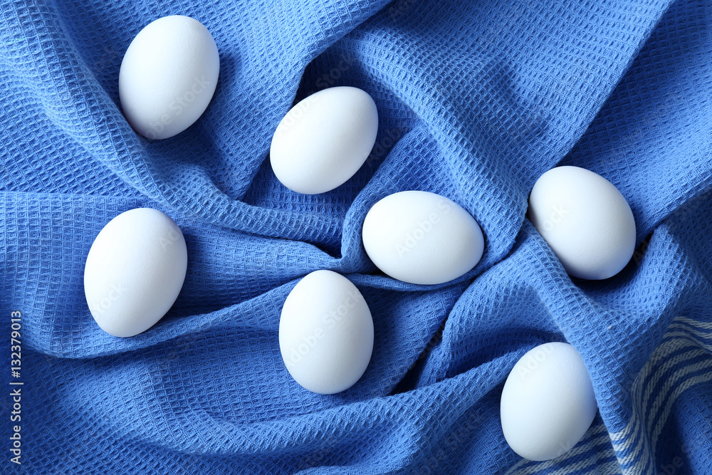 Raw eggs on blue fabric background