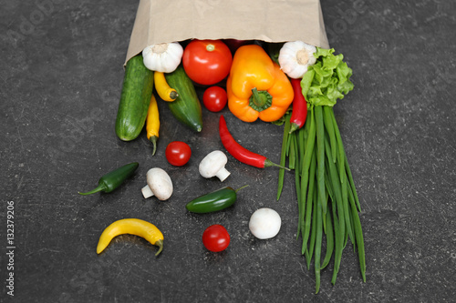 Bag of fresh vegetables on gray background
