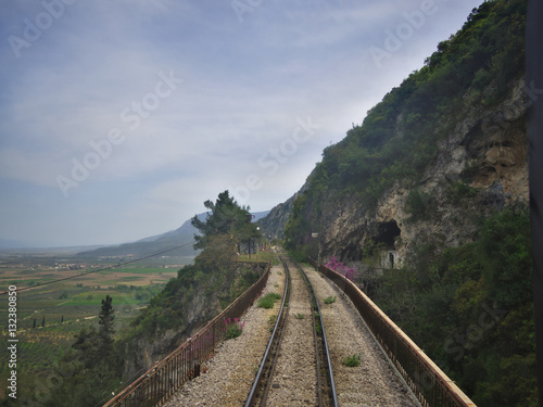 View through rear window of train travelling through mountains..