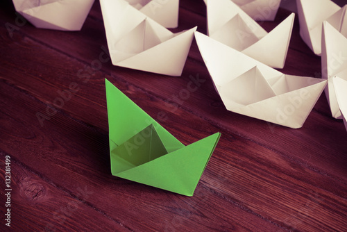 Business leadership concept with white and color paper boats on 