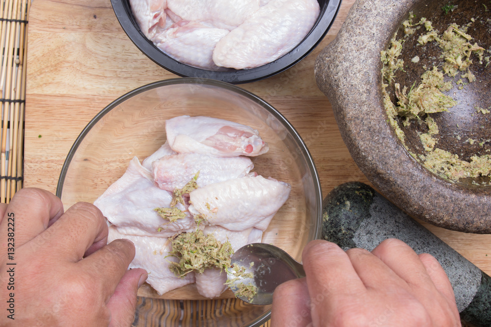 Chef putting seasoning to chicken wings for cooking Chef putting seasoning to chicken wings for cooking