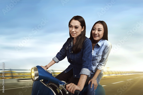 Two young asian woman riding a motorbike