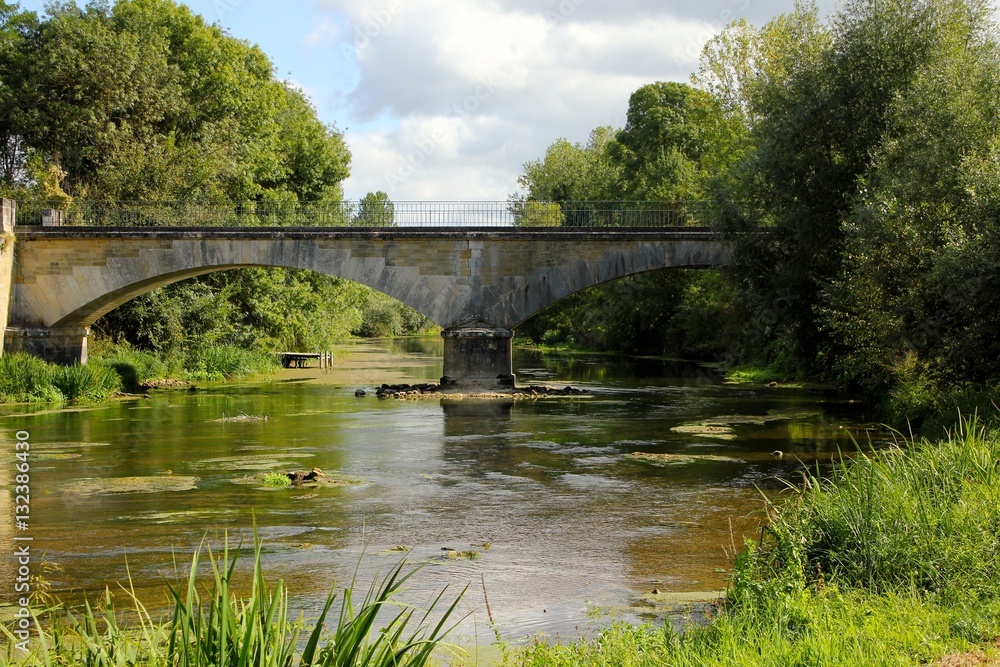 Slow flowing river with age old archway bridge