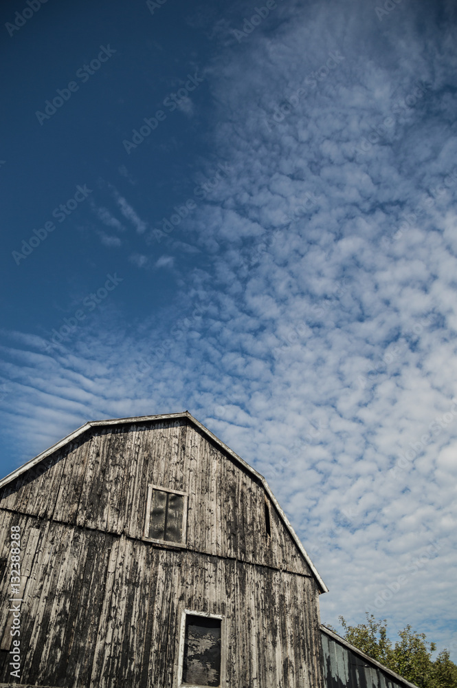 Gambrel roof black weathered barn with deep blue sky and cloudsc Gambrel roof black weathered barn with deep blue sky and cloudsc