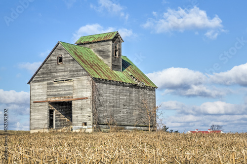 A rustic old barn stands dramatically against a cloudy blue sky in a rural Ohio cornfield.