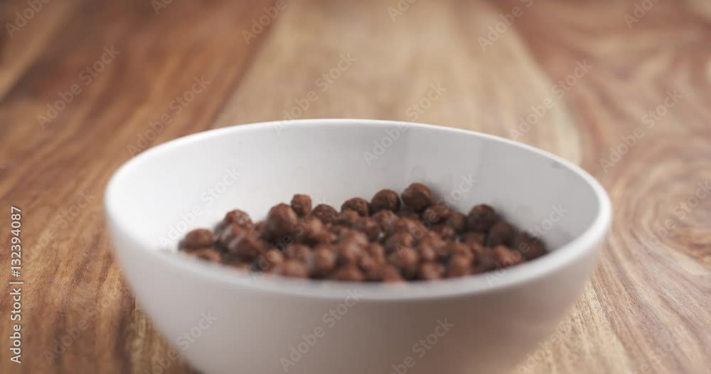 chocolate cereal balls with milk in white bowl on wood table slide movement, 4k prores footage chocolate cereal balls with milk in white bowl on wood table slide movement, 4k prores footage