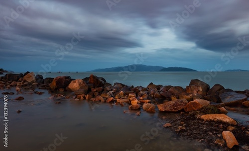 A cloudy evening sky over the south china sea with a rock formation and vinpearl island in the distance, Vietnam.