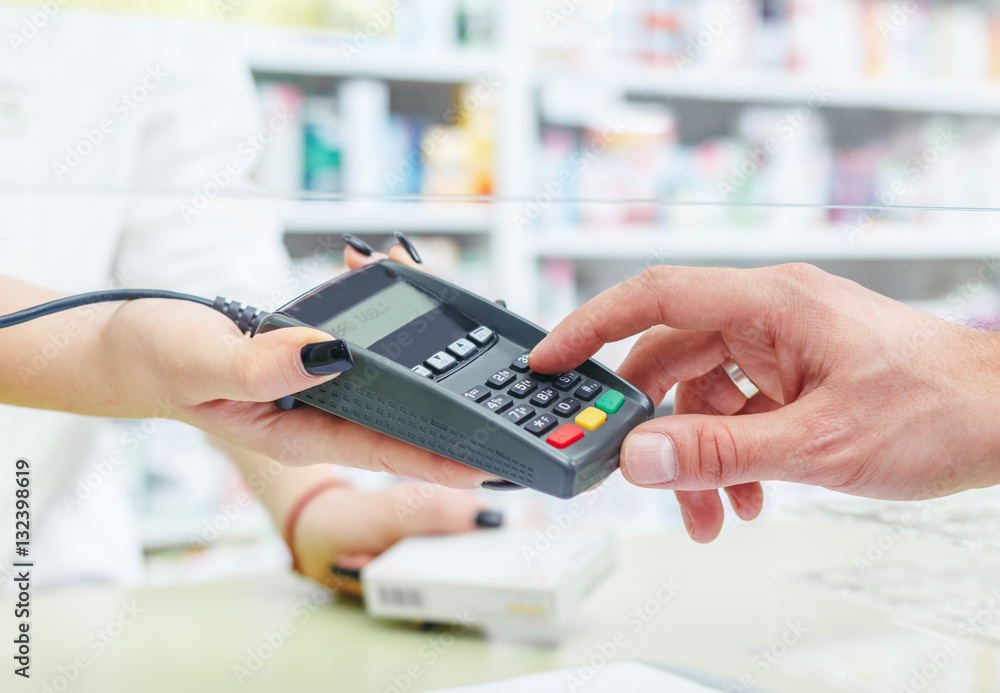 Shopping at the pharmacy with a credit card and entering a security pin on the terminal, hands close up Shopping at the pharmacy with a credit card and entering a security pin on the terminal, hands close up