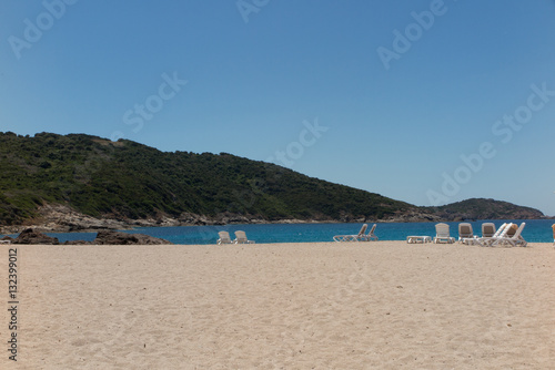 View of the blue sea paradisiac with the beach chairs and the mountains or hills behind