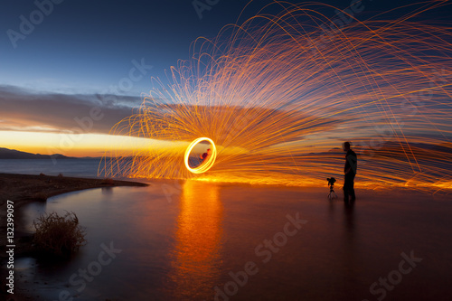 Photographer in lake shooting picture of spinning sparks at sunset. Pyramid Lake, NV.