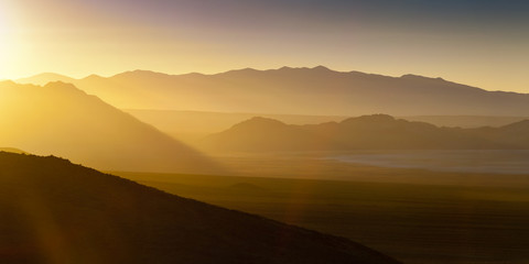 Acrylglasbilder Orange Desert landscape sunset with sun flare and haze  © neillockhart