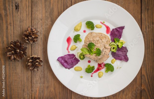 Pork medallions in cream sauce and micro greens on a white plate. Wooden background. Top view. Close-up