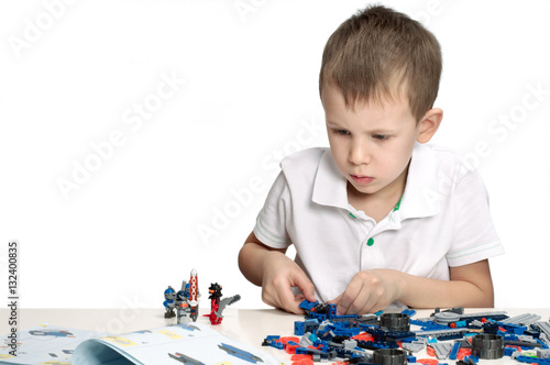 Young boy playing absorbedly with construction kit. With place for a text.