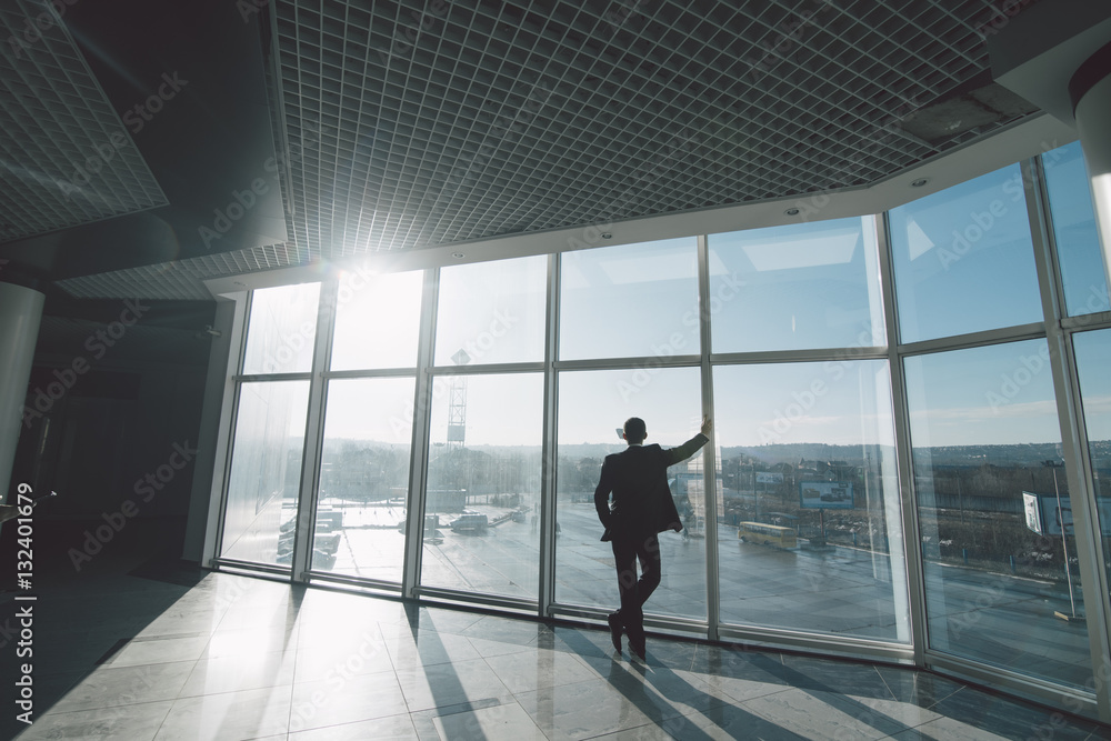 Time to think. Business man alone in room with panoramic windows.