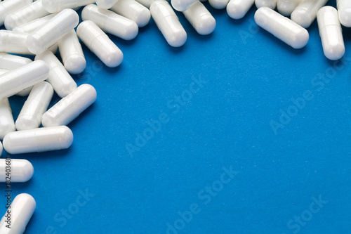 White capsules medications on blue background. Copy space for your text, high resolution product photo