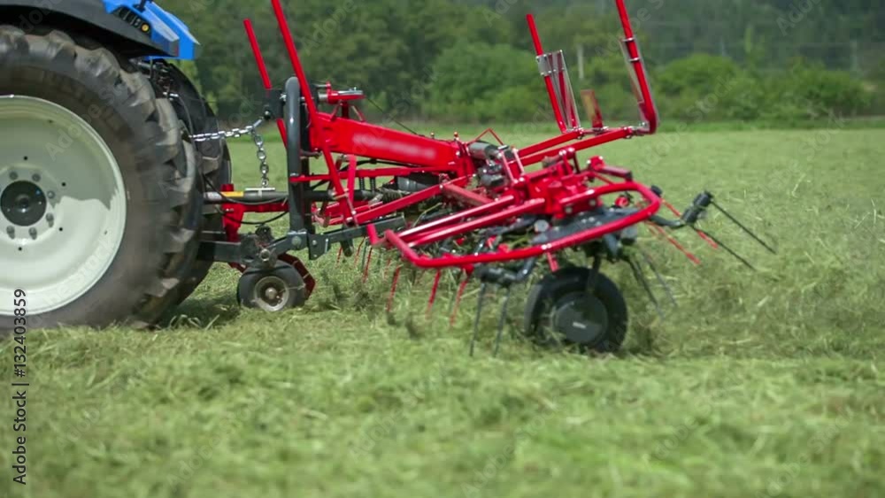 Straws are flying everywhere around when a young farmer on a blue tractor is preparing hay with rotary hay rakes. The rakes are moving incredibly fast.
Straws are flying everywhere around when a young farmer on a blue tractor is preparing hay with rotary hay rakes. The rakes are moving incredibly fast.