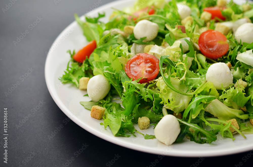 Fresh salad on a white plate on a black table