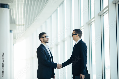 Boss and manager agree handshake in office panoramic room