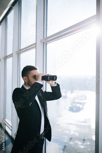 Businessman with binoculars spying on competitors.