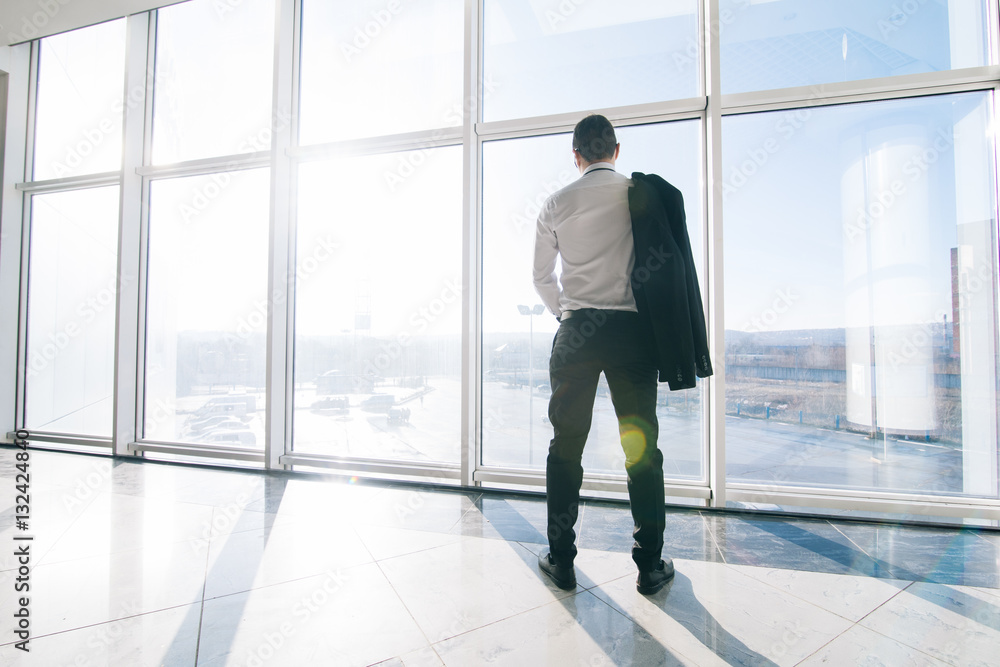 Young relaxed businessman with jacket over shoulders in modern office panoramic windows Young relaxed businessman with jacket over shoulders in modern office panoramic windows