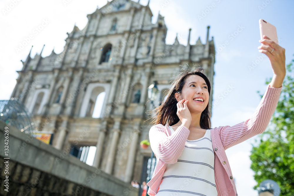 Naklejka premium Woman taking selfie by mobile phone in Macao city