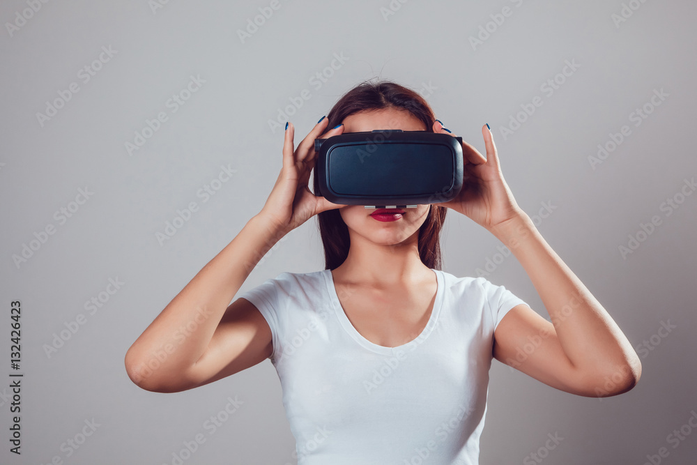 Attractive woman using virtual reality goggles on grey background. VR headset. Attractive woman using virtual reality goggles on grey background. VR headset.
