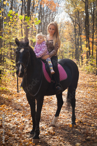 young mother with a daughter walk in autumn forest with a horse © izida1991