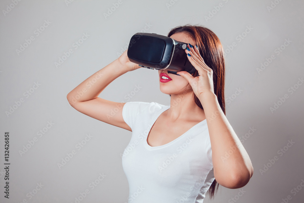 Attractive woman using virtual reality goggles on grey background. VR headset. Attractive woman using virtual reality goggles on grey background. VR headset.