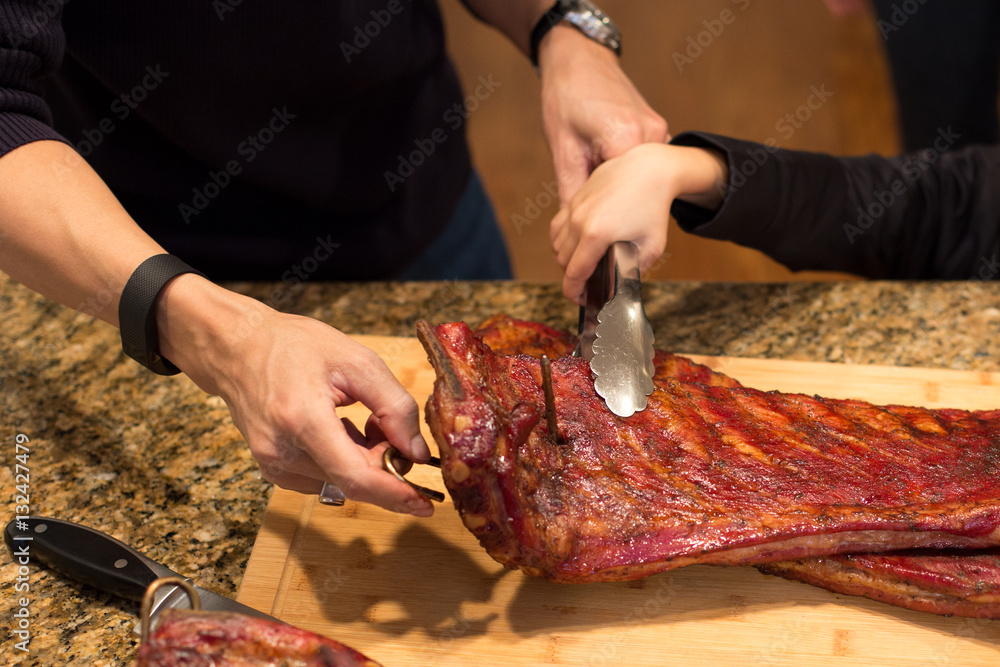 Father and son hand holding spare ribs on wooden board on family
