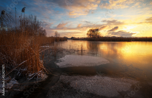 Winter landscape with sunset sky and frozen river. Daybreak