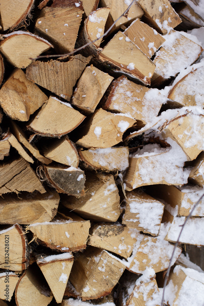 Chopped firewood logs in a pile with snow Chopped firewood logs in a pile with snow