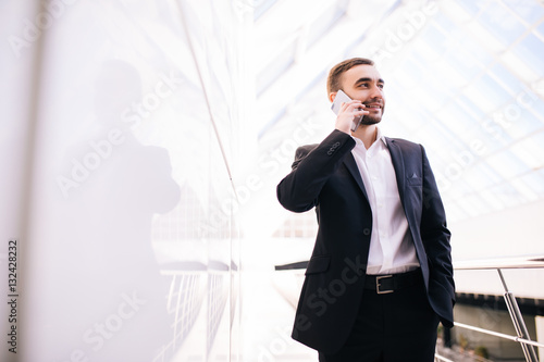 Young businessman speak on phone and walking around office