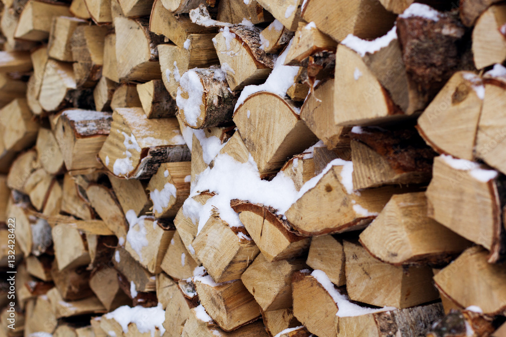 Chopped firewood logs in a pile with snow Chopped firewood logs in a pile with snow