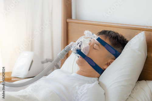 Obstructive sleep apnea therapy, Man wearing CPAP mask.
CPAP:Continuos positive airway pressure  therapy.Happy and healthy senior man breathing more easily during sleep  on his back without snoring.