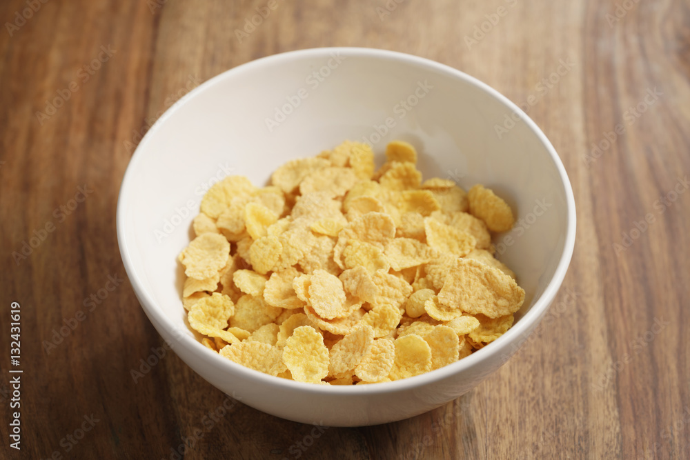 dry corn flakes in white bowl on wood table, breakfast foods dry corn flakes in white bowl on wood table, breakfast foods