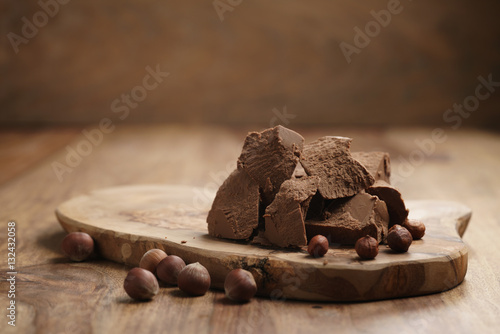 chunks of gianduja with hazelnuts on wood board, premium chocolate dessert photo