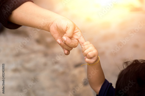 Fotografie Little child holding her mother's finger while walking outside