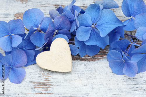 blue flower and wooden heart lying on wood